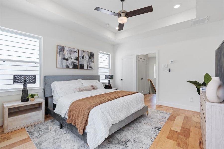 The primary bedroom, adorned with two windows on the exterior wall, offers an abundance of natural light and a serene ambiance, enhanced by the warmth and durability of engineered floors.