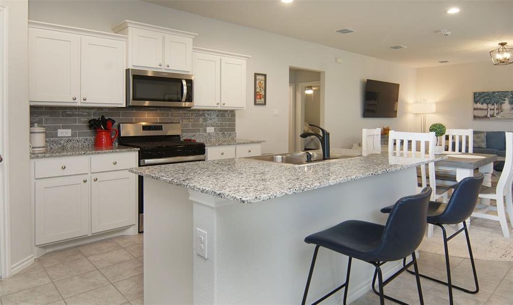 Kitchen with tasteful backsplash, sink, an island with sink, white cabinetry, and stainless steel appliances