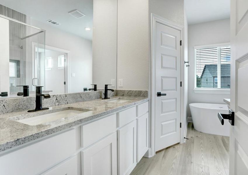 Master bathroom with designer matte black fixtures, granite countertops, and white cabinetry.