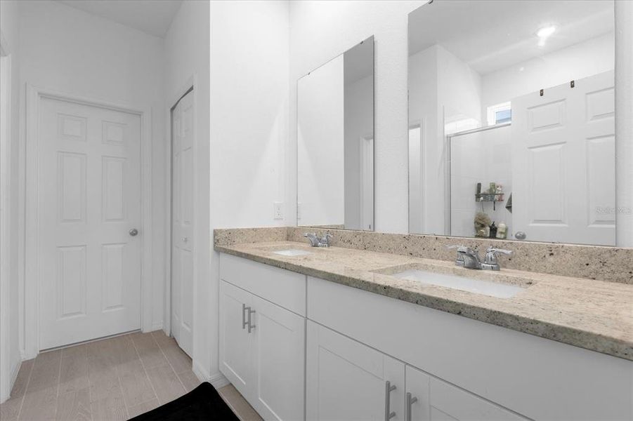 master bathroom with double vanity sinks and granite
