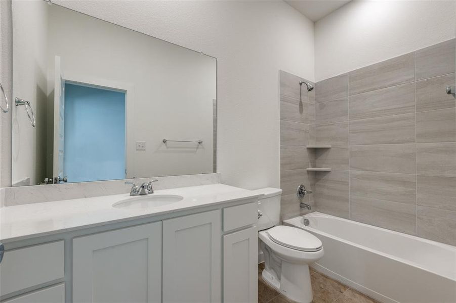 Full bathroom featuring tile patterned floors, toilet, vanity, and tiled shower / bath