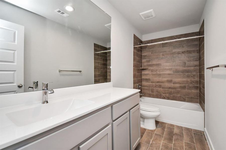 Indulge in refined charm in the secondary bathroom, where the tile flooring harmonizes with a bath/shower combo surrounded by tasteful tile. Slate wood cabinets, double sinks coupled with a gorgeous countertop, elevate the space, cultivating a truly welcoming atmosphere.