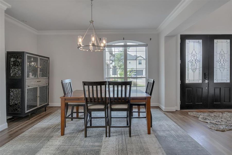 Dining area featuring ornamental molding, an inviting chandelier, french doors, and wood-type flooring