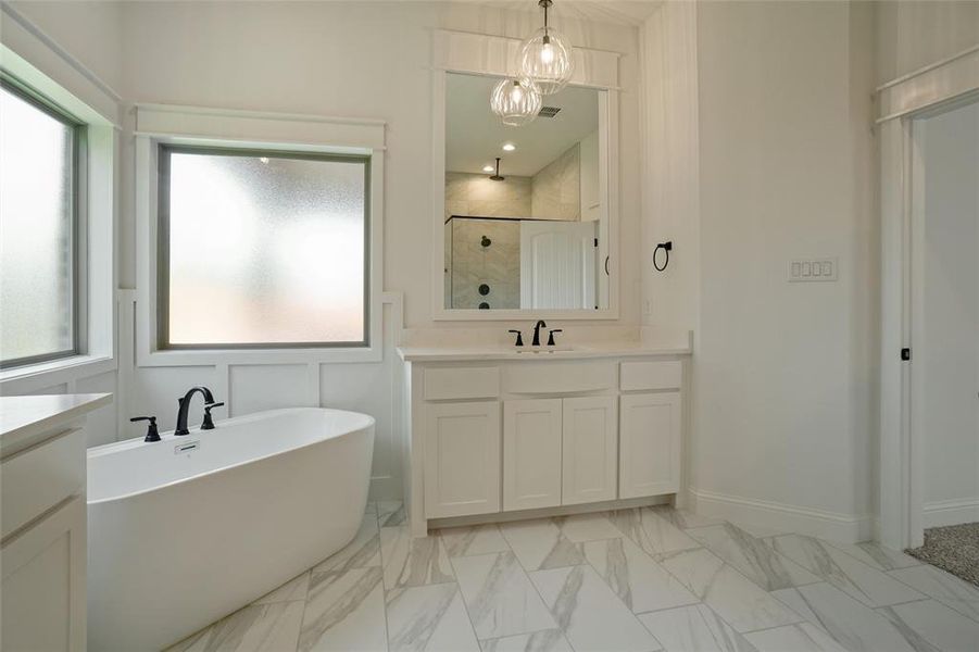 Bathroom with tile floors, vanity with extensive cabinet space, and shower with separate bathtub