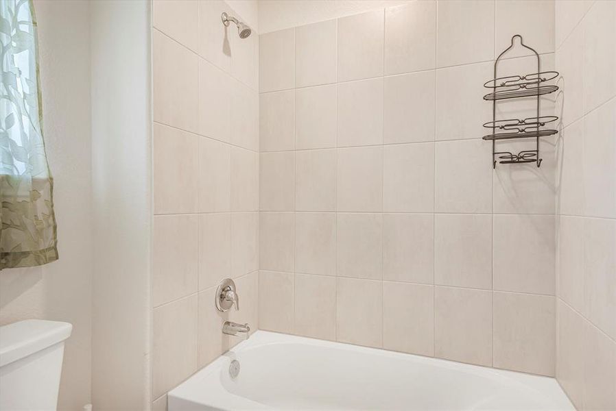 Bathroom with tiled shower / bath and toilet