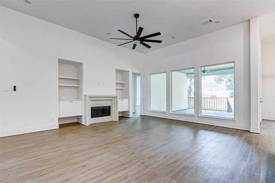 Welcome to your spacious family room! Features include hardwood floors, tall ceilings, recessed lights, a ceiling fan, custom built-is, bright windows, and a fireplace.