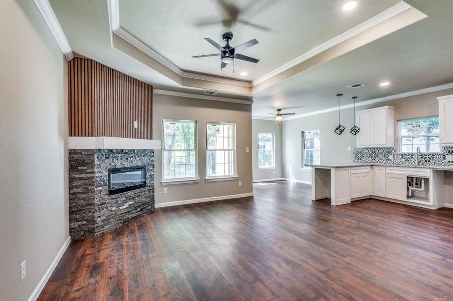 Kitchen with dark hardwood / wood-style floors, a fireplace, pendant lighting, ceiling fan, and white cabinets