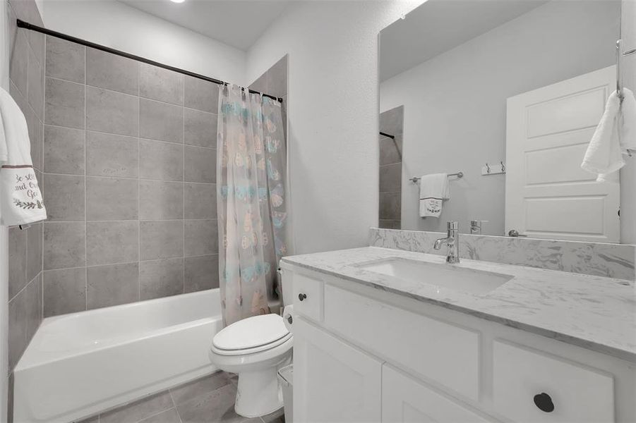 Full bathroom with tile patterned flooring, vanity, toilet, and shower / bath combination with curtain