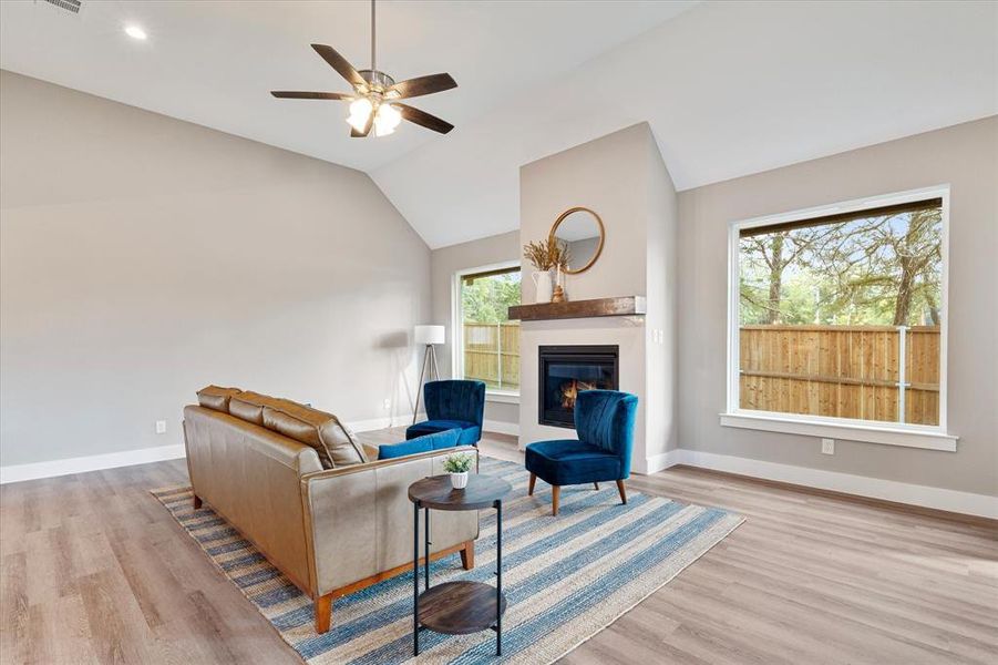 Living room featuring ceiling fan, light hardwood / wood-style flooring, lofted ceiling, and a healthy amount of sunlight