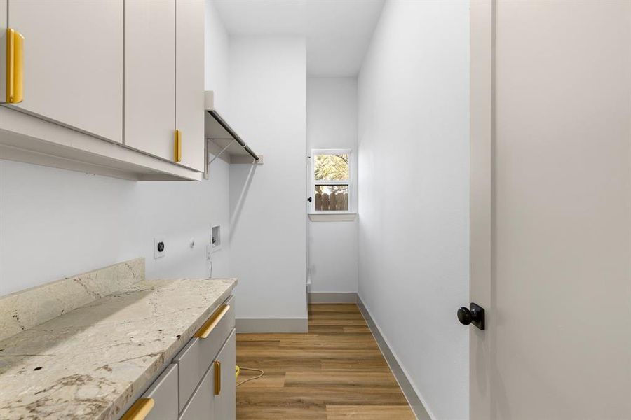 Laundry area featuring hookup for an electric dryer, hookup for a washing machine, light hardwood / wood-style flooring, and cabinets