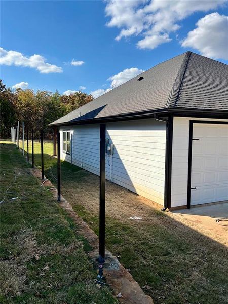 View of property exterior featuring a garage and a lawn