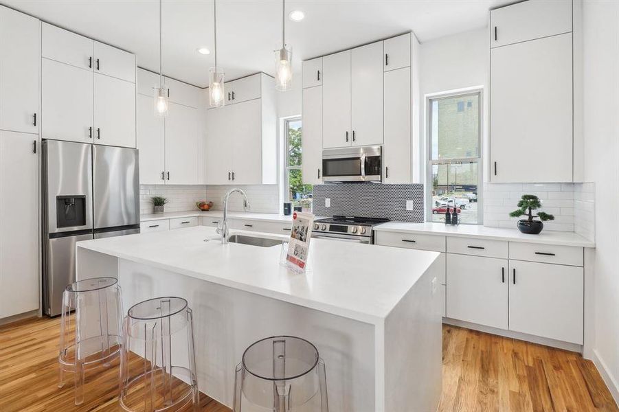 Kitchen with backsplash, light hardwood / wood-style flooring, and appliances with stainless steel finishes