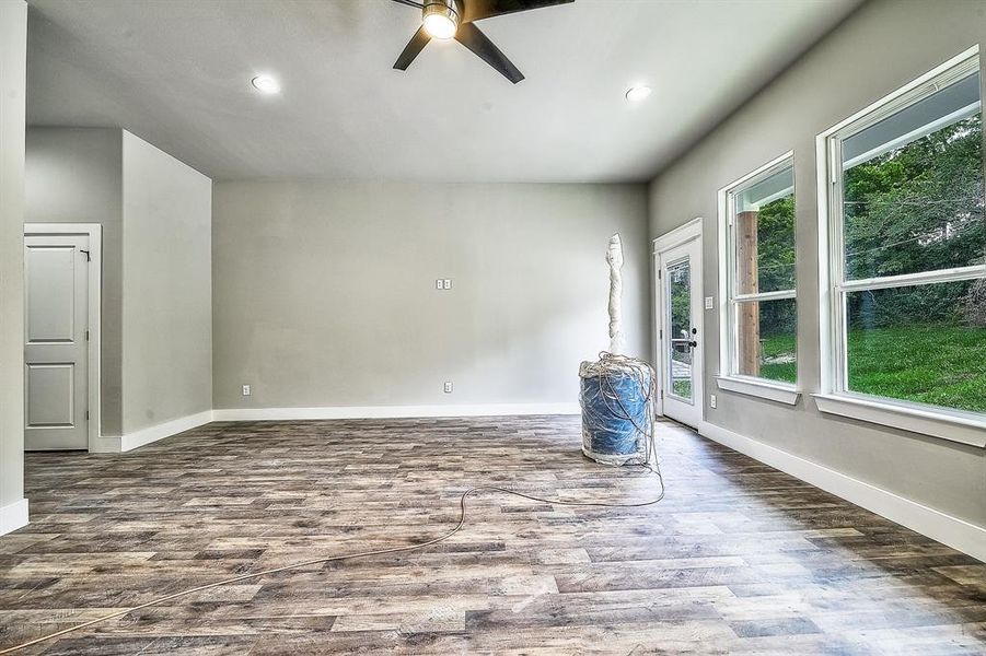 Spare room featuring dark hardwood / wood-style floors, ceiling fan, and a healthy amount of sunlight