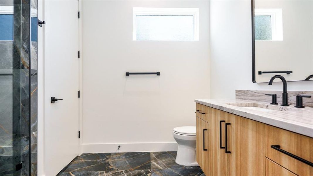 Bathroom featuring toilet, a wealth of natural light, a shower with door, and vanity