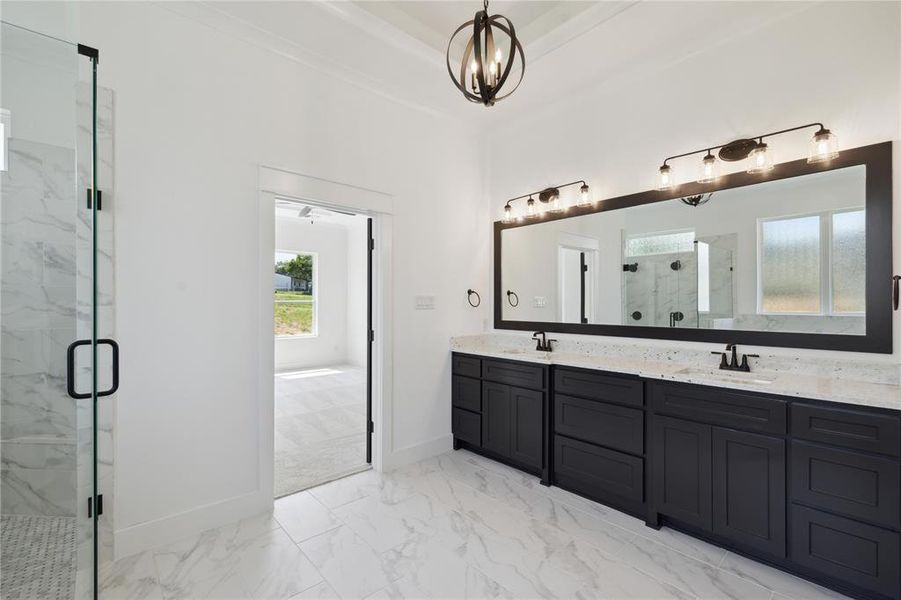 Bathroom with a shower with door, vanity, and an inviting chandelier