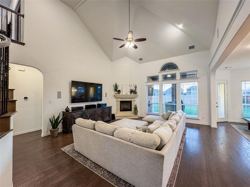 Living room with ceiling fan, high vaulted ceiling, and dark hardwood / wood-style flooring