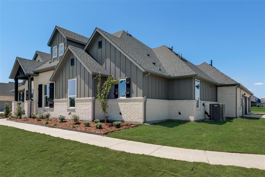 View of side of home with cooling unit and a yard