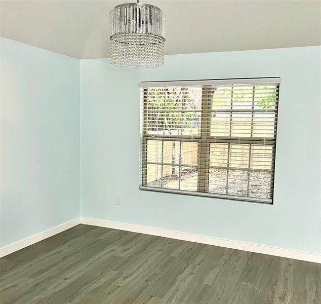 Unfurnished room featuring a notable chandelier, dark hardwood / wood-style floors, and vaulted ceiling