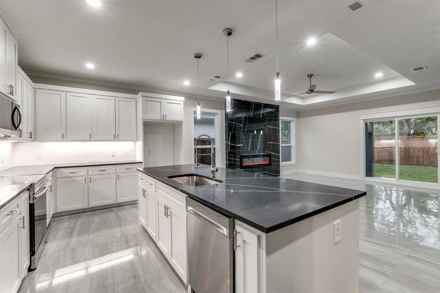 Kitchen featuring white cabinets, a kitchen island with sink, sink, decorative light fixtures, and stainless steel appliances