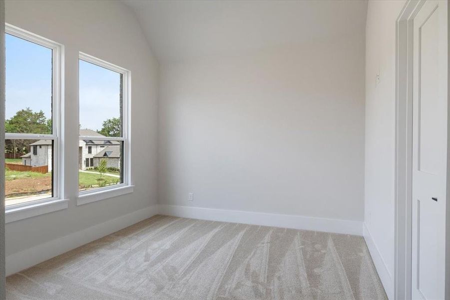 Empty room featuring vaulted ceiling and light colored carpet