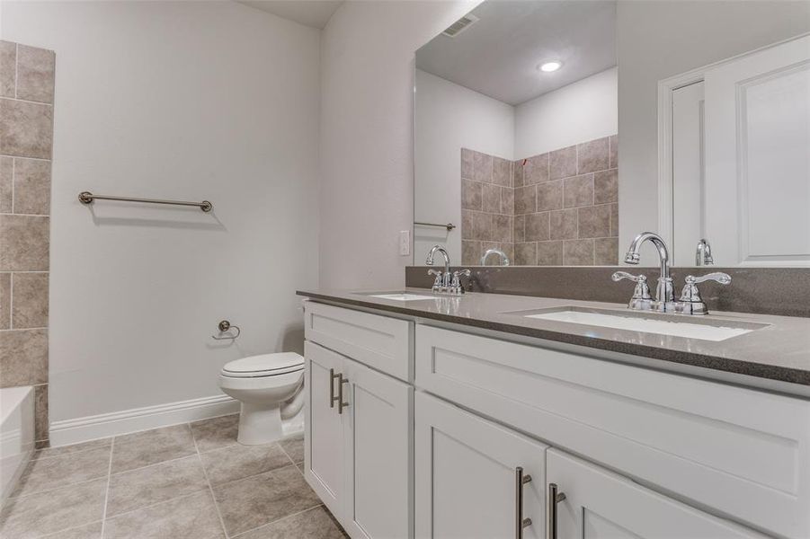 Bathroom featuring dual vanity, tile flooring, and toilet