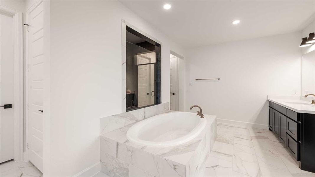 Bathroom featuring vanity and a relaxing tiled tub