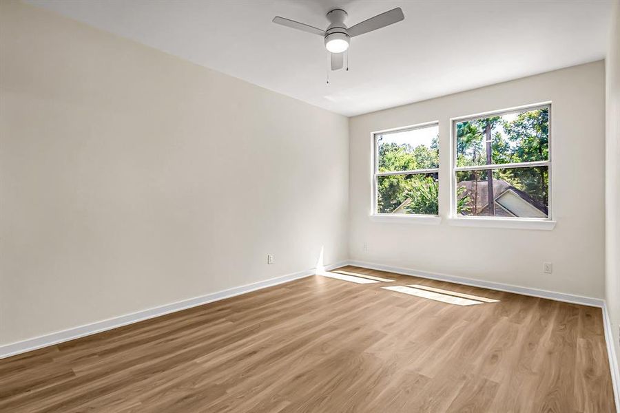 The primary bedroom is filled with natural light from the windows that overlook the front yard.