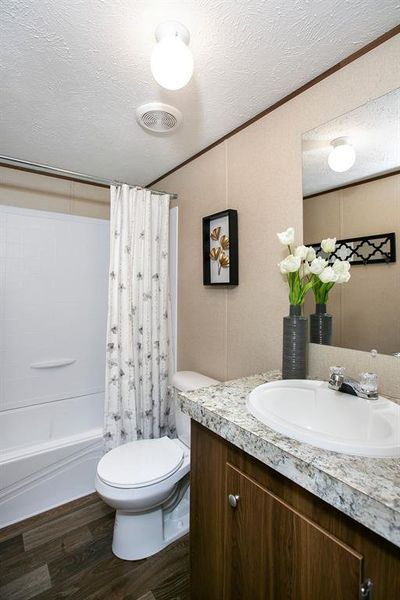 Full bathroom featuring vanity, toilet, shower / bath combo, a textured ceiling, and hardwood / wood-style floors