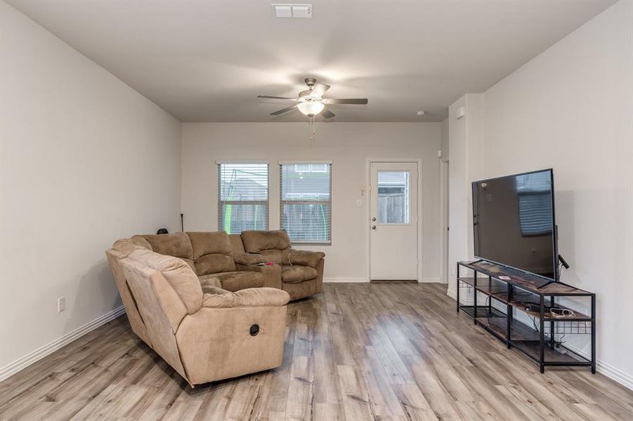 Living room with light hardwood / wood-style floors and ceiling fan