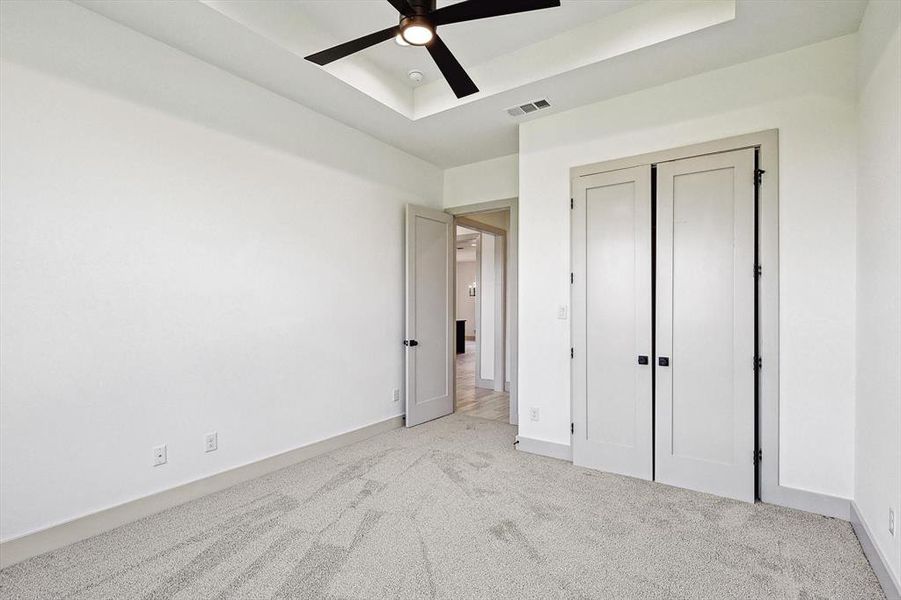 Unfurnished bedroom featuring light carpet, ceiling fan, and a closet