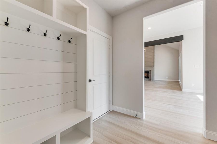 Mudroom with a brick fireplace and light hardwood / wood-style floors