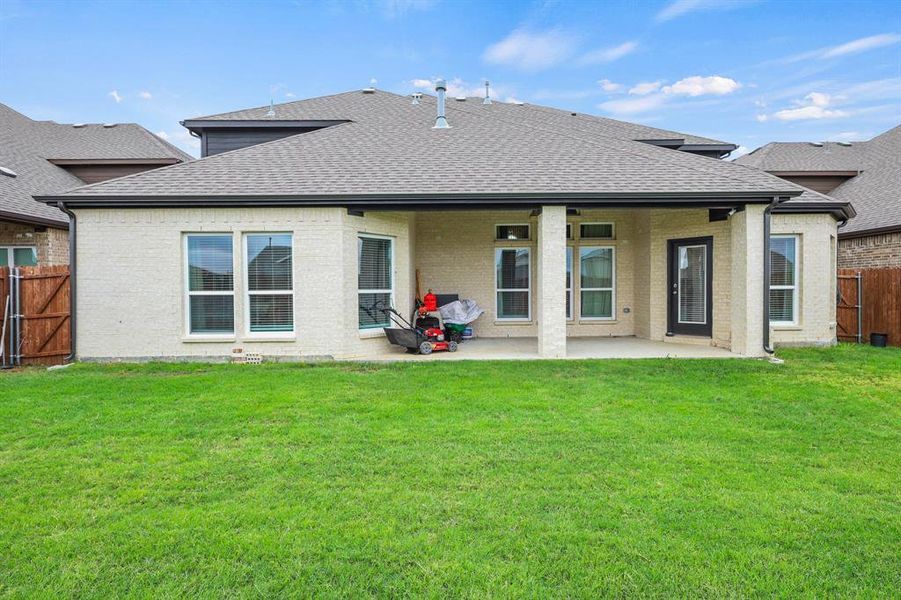 Rear view of property featuring a lawn and a patio