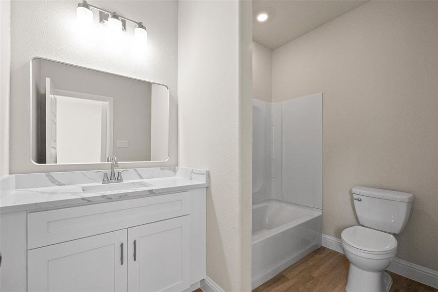 Full bathroom featuring vanity, toilet, bathtub / shower combination, and hardwood / wood-style floors