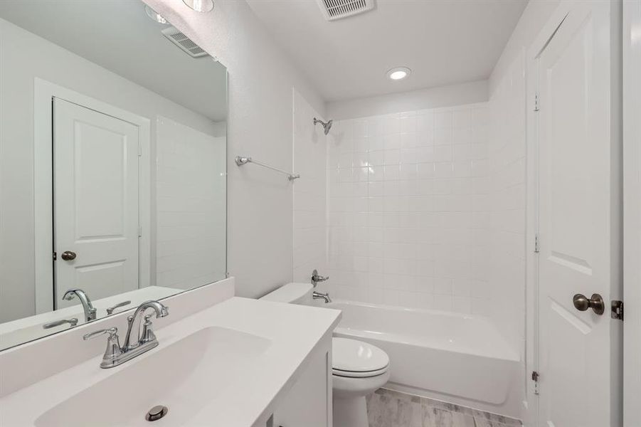 Full bathroom featuring vanity, tiled shower / bath, and toilet