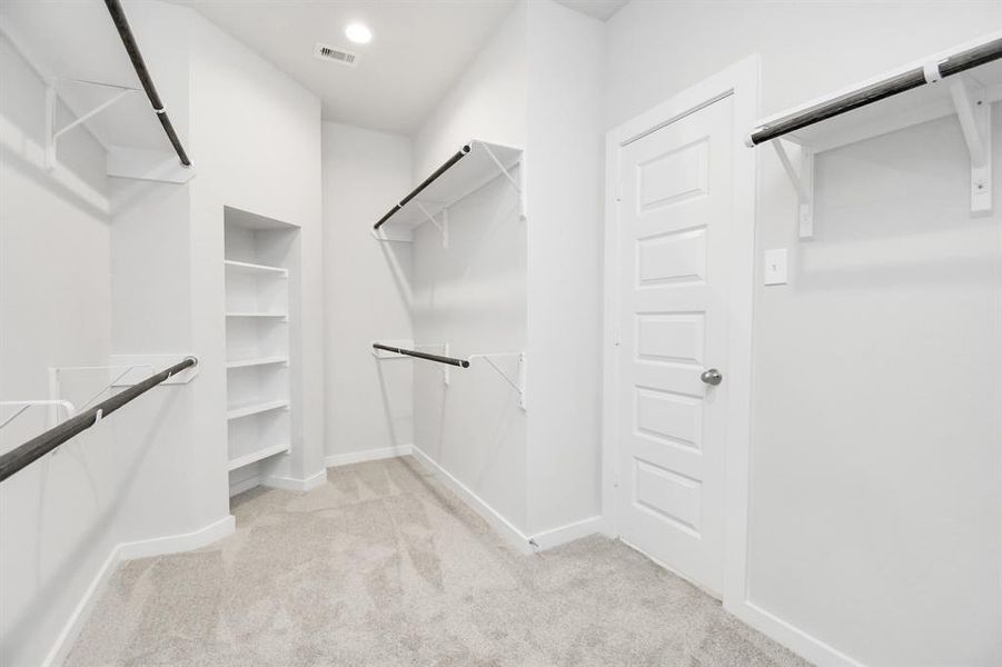 Spacious walk-in closet with high ceilings, built-ins,  and plush carpet.