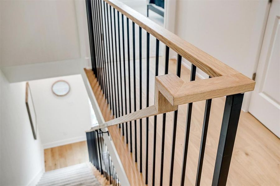 The stair railing, crafted from white oak and iron, adds a touch of elegance to the home's interior, blending modern design with natural elements for a timeless aesthetic.