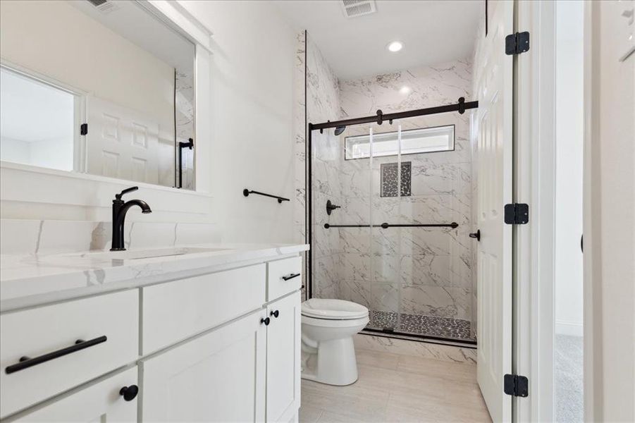 Bathroom with walk in shower, tile floors, tasteful backsplash, vanity, and toilet