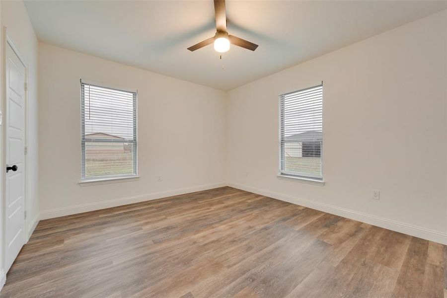 Spare room with ceiling fan, light wood-type flooring, and plenty of natural light