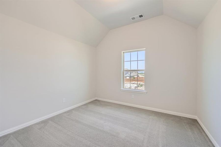 Carpeted empty room featuring vaulted ceiling