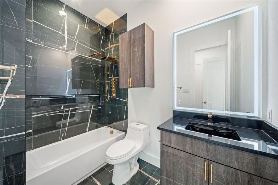 Bathroom featuring tile floors, vanity with extensive cabinet space, tile walls, a tile shower, and toilet