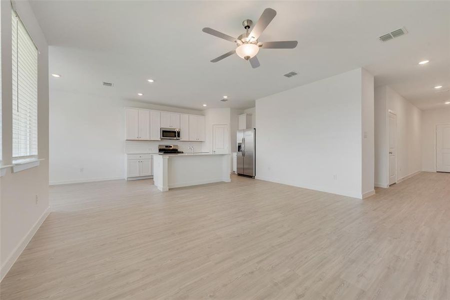 Unfurnished living room featuring ceiling fan and light hardwood / wood-style flooring