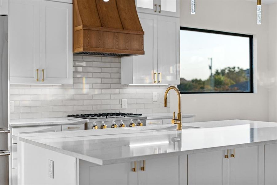 Kitchen with white cabinets, sink, high end fridge, backsplash, and custom range hood