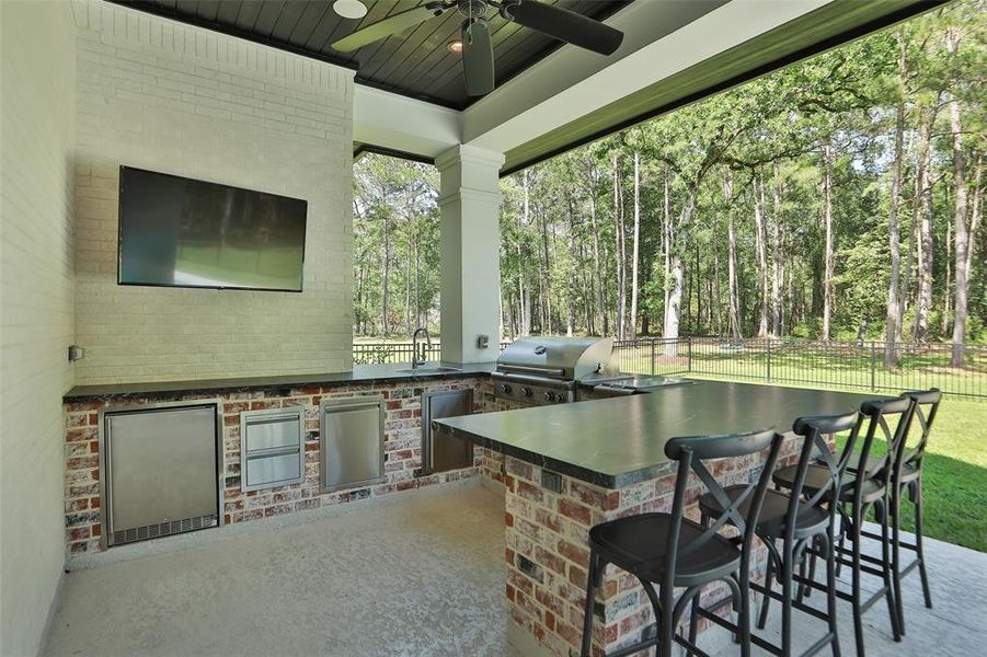 Awesome outdoor kitchen with stunning (leather like) quartz, spectacular bar area, refrigerator, grill, and sink.