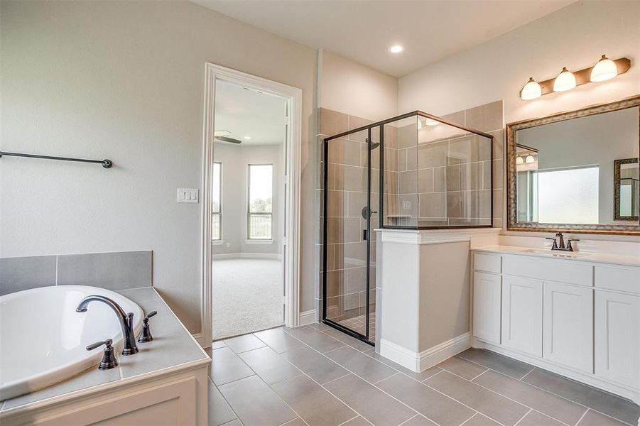 Bathroom with tile patterned floors, vanity, and separate shower and tub