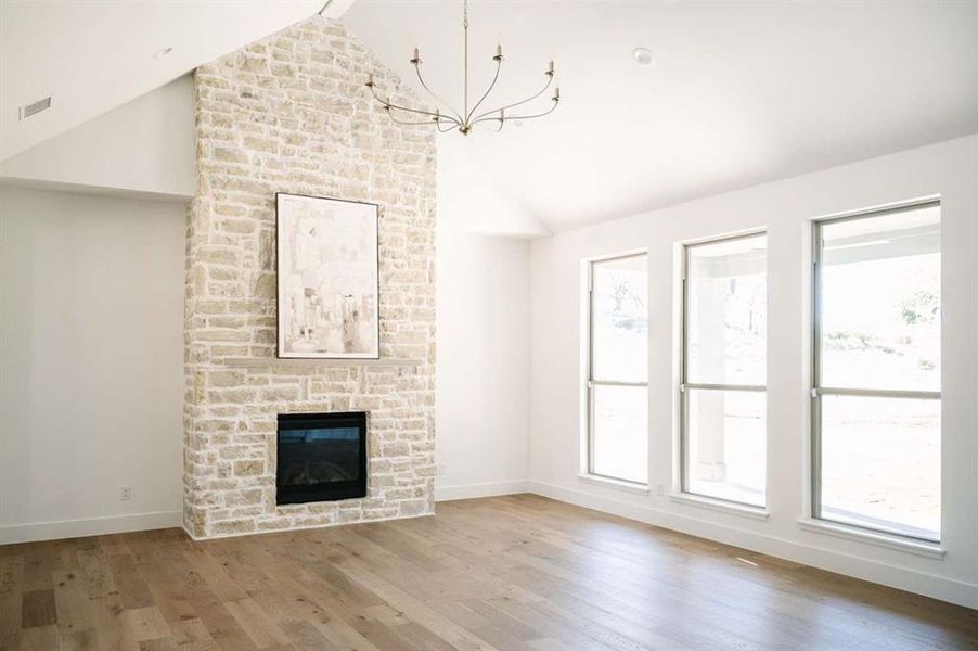 Unfurnished living room featuring a fireplace, hardwood / wood-style floors, lofted ceiling with beams, and a wealth of natural light