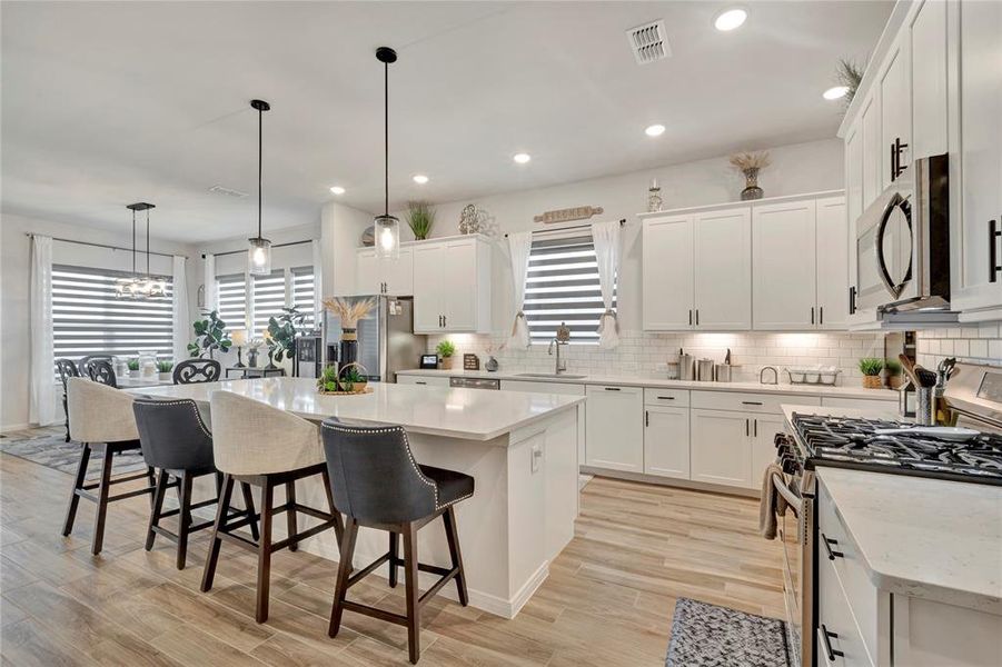 Chef's Delight Kitchen - Beautiful lighting, ample cabinetry, counter space, and a dining area in the distance. Gas range, microwave, and dishwasher included, perfect for culinary enthusiasts.