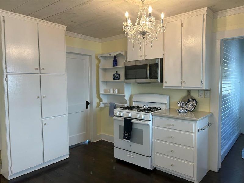 Kitchen with white cabinets, gas range gas stove, and dark hardwood / wood-style flooring