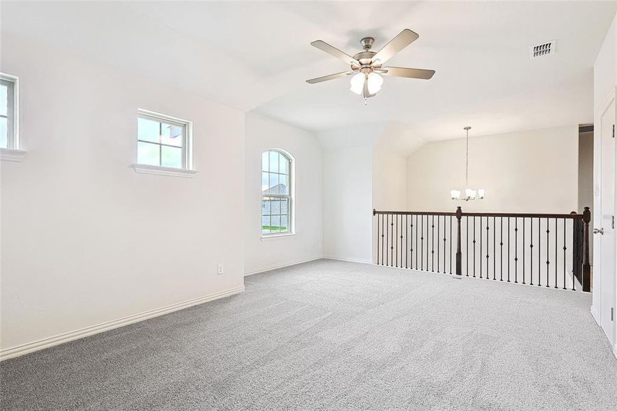 Spare room with lofted ceiling, ceiling fan with notable chandelier, and carpet floors