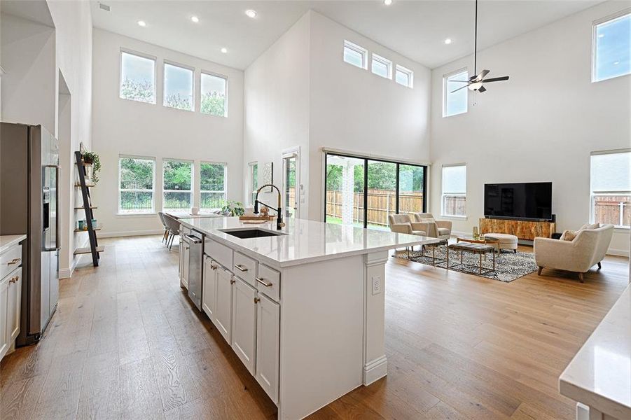 Kitchen featuring stainless steel appliances, hardwood / wood-style floors, white cabinets, sink, and a kitchen island with sink