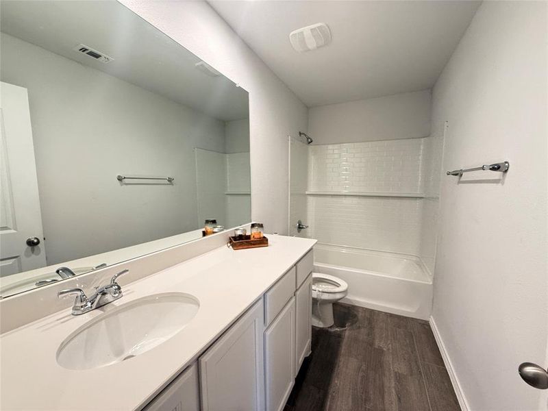 Full bathroom with hardwood / wood-style floors, vanity, toilet, and bathing tub / shower combination